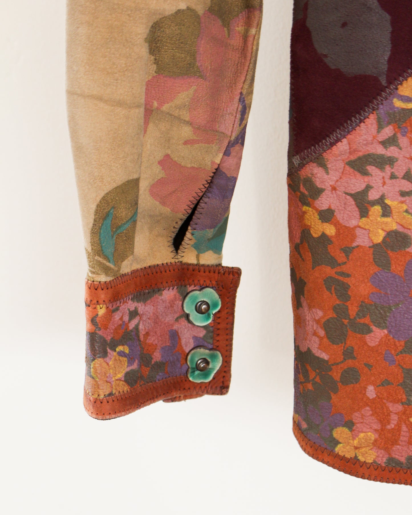 Close-up of colorful floral-patterned fabric with a button on a beige background