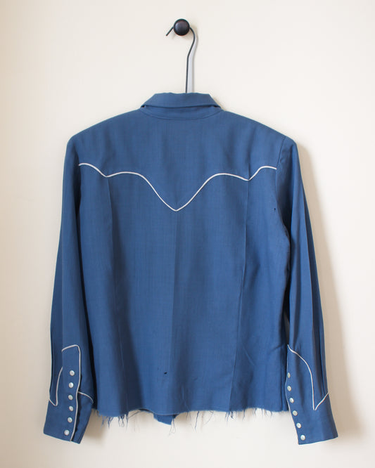 Blue jacket with white stitching on a hanger against a beige background