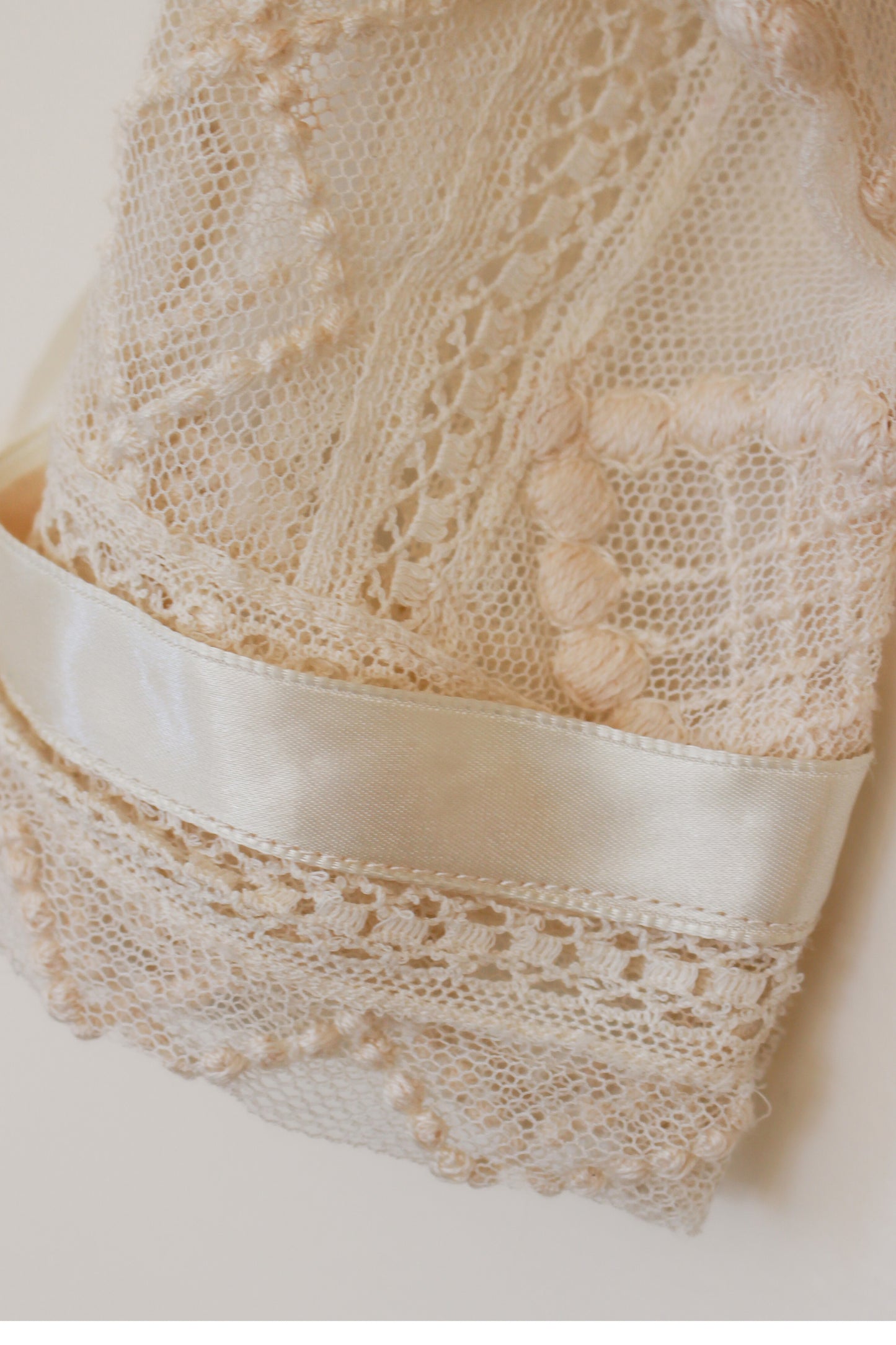 Close-up of lace fabric with a satin ribbon on a neutral background