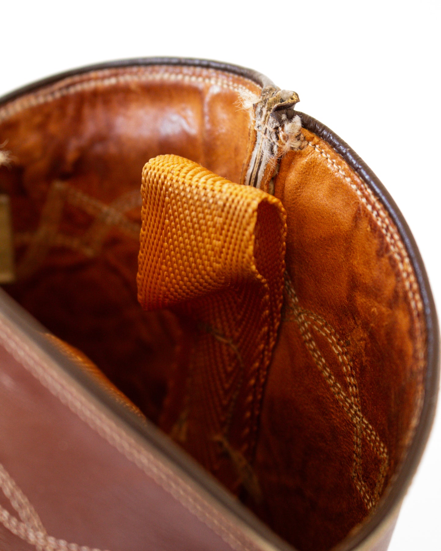 Close-up of a brown leather bag with a textured orange tag.