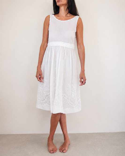 Woman wearing a white sleeveless dress against a plain background