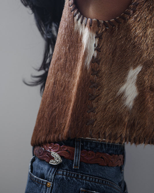 Side view of woman in vest and denim jeans on a white background.