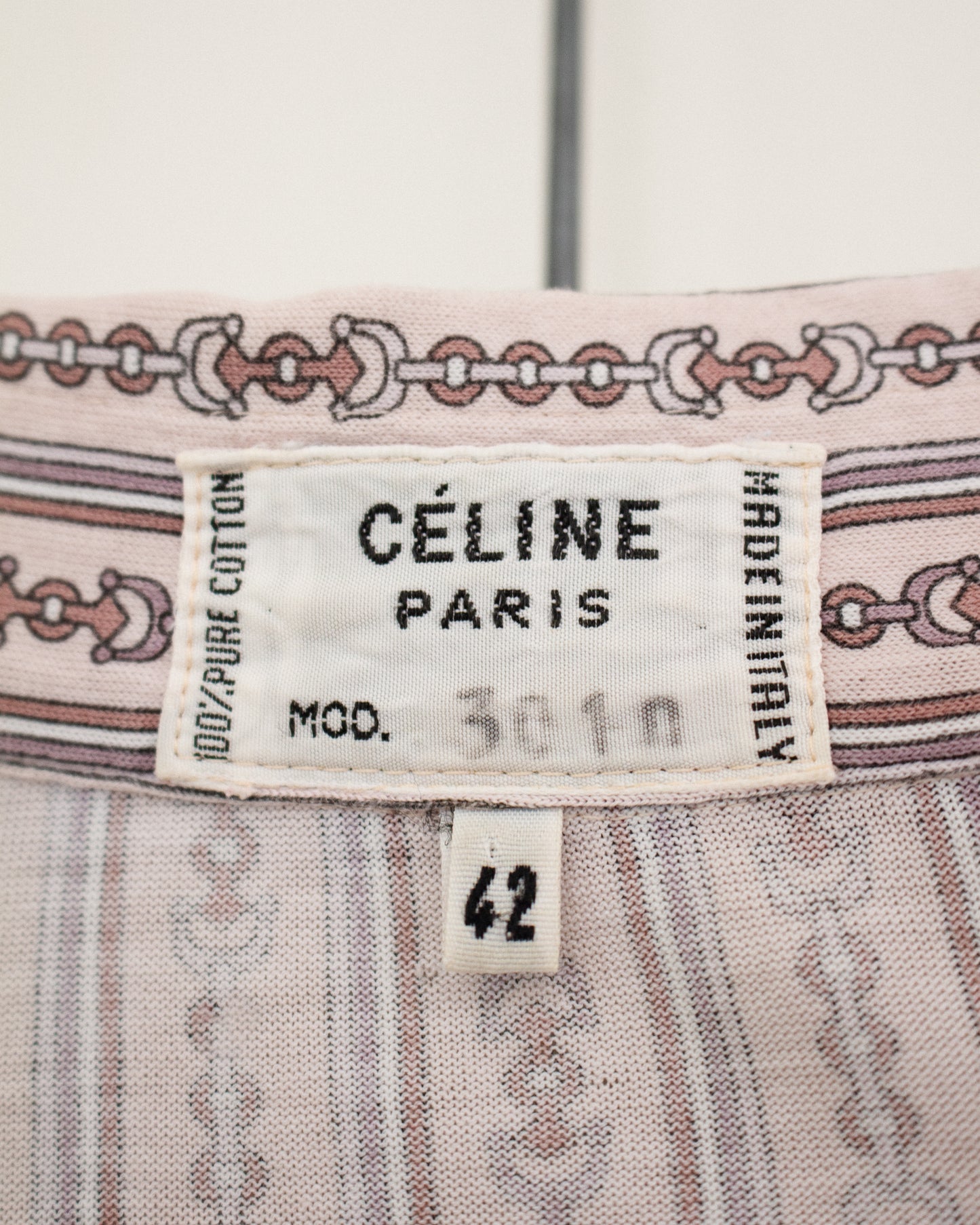 Close-up of a Céline Paris garment label on a light pink patterned textile, with a size tag reading 42.