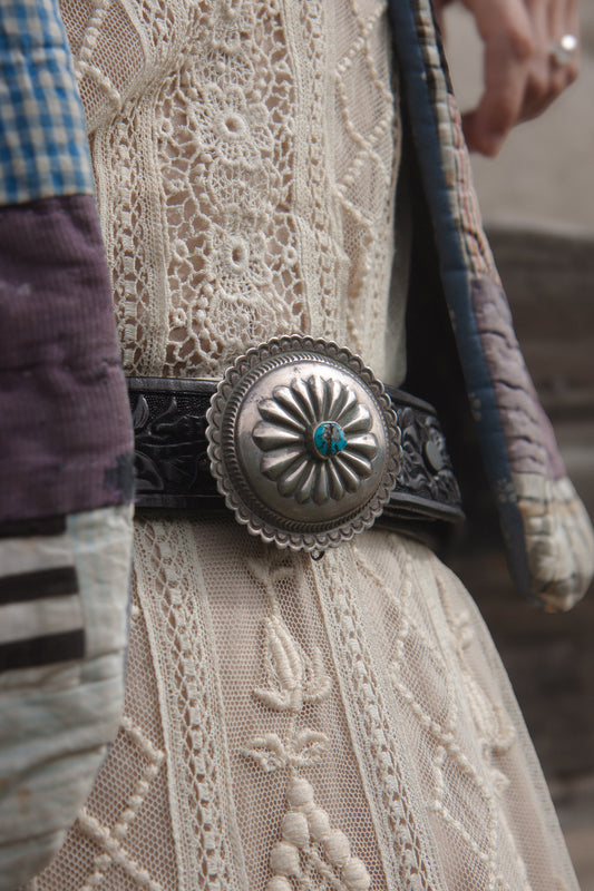 Close-up of a decorative belt buckle on a textured fabric background