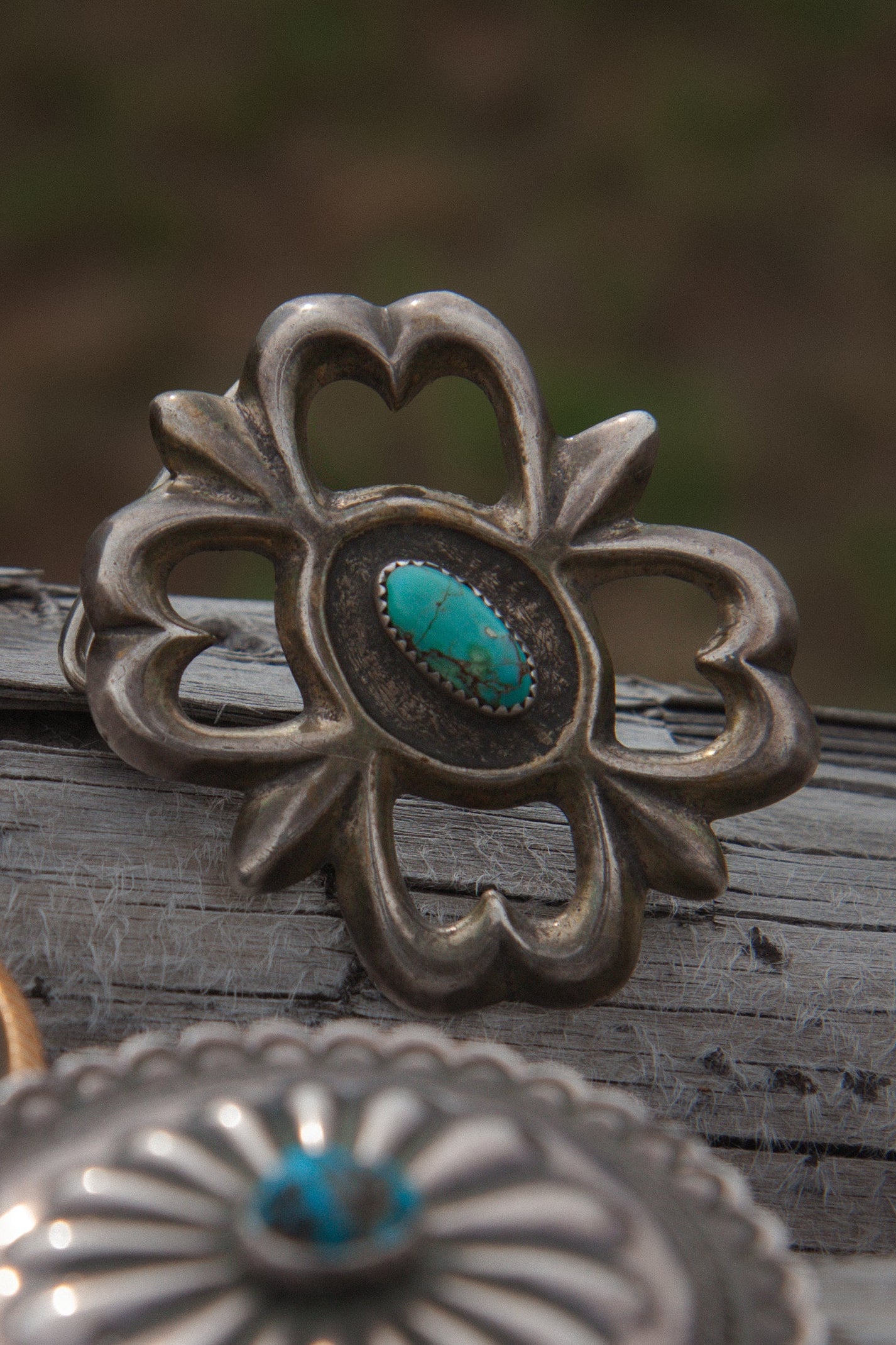 Silver concho with turquoise stone on a wooden surface