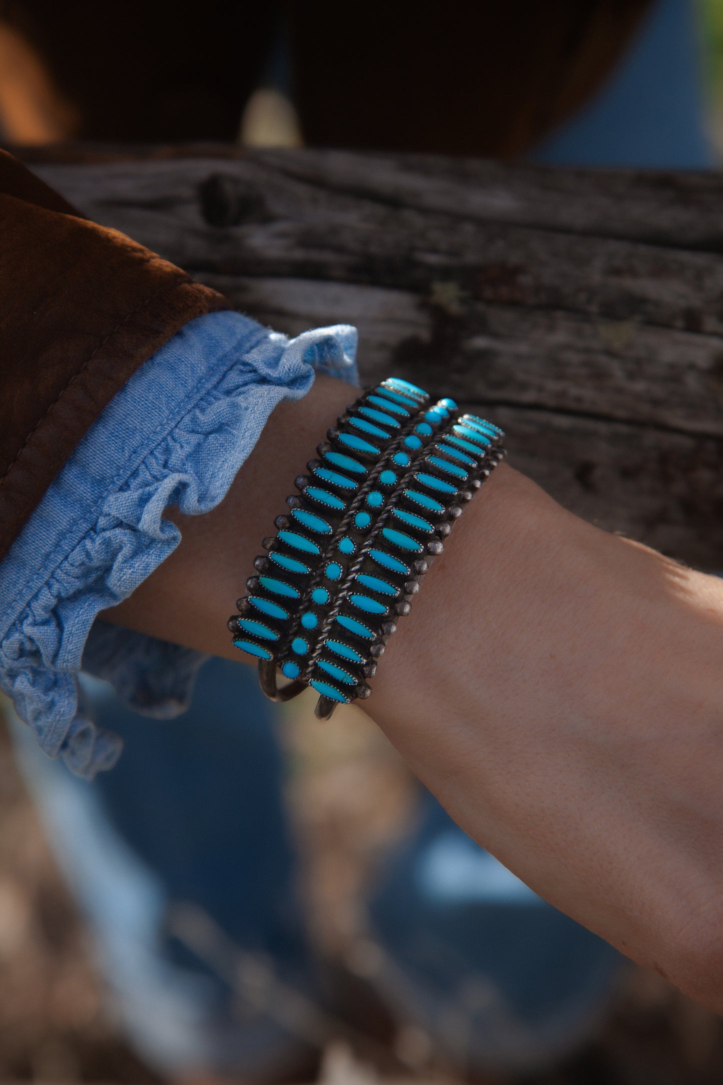 Close-up of a wrist wearing a turquoise beaded bracelet with a blurred background