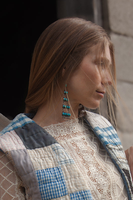 Woman wearing a quilted jacket with a checkered pattern, standing outdoors.