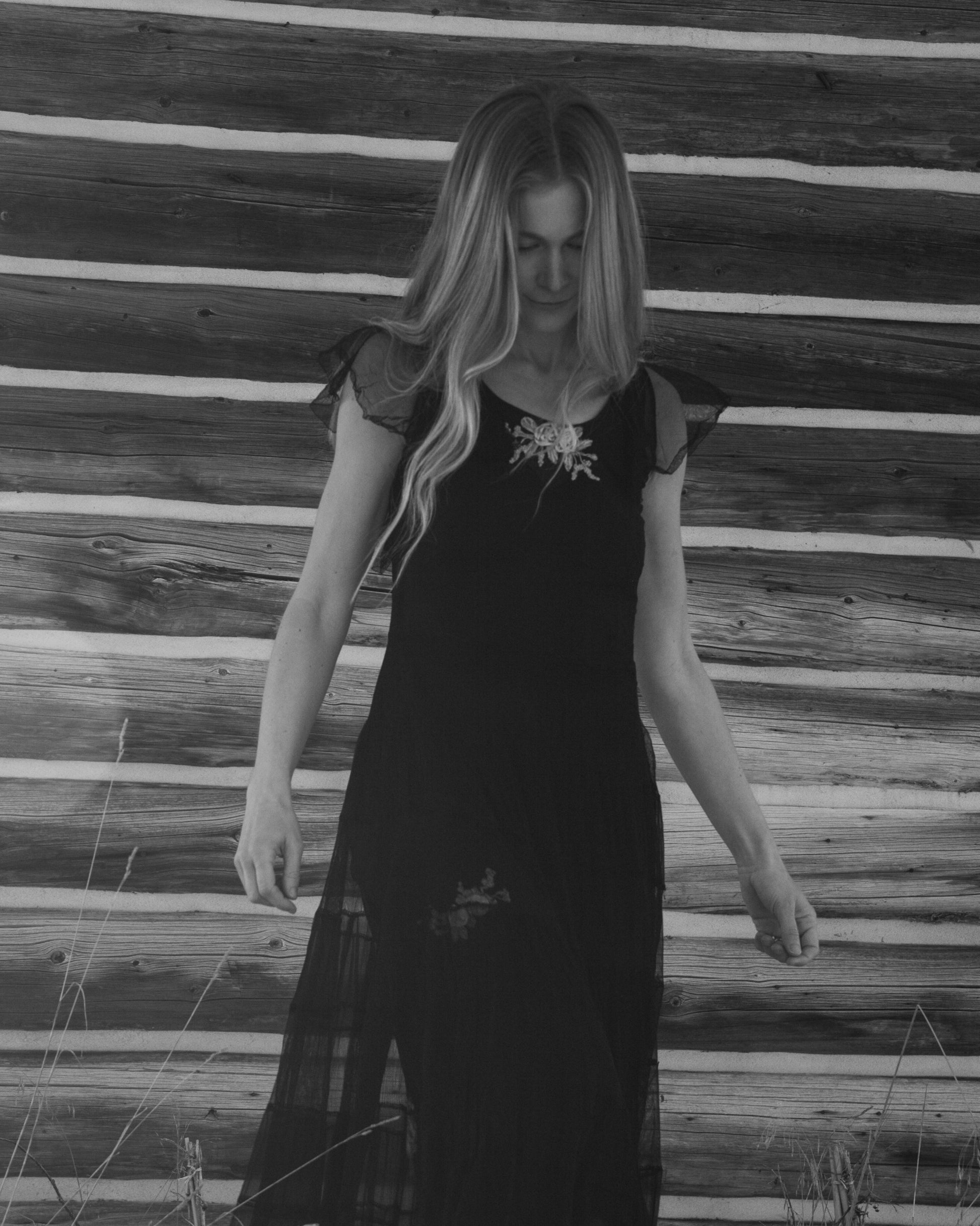 Woman wearing a black dress with floral details against a wooden background