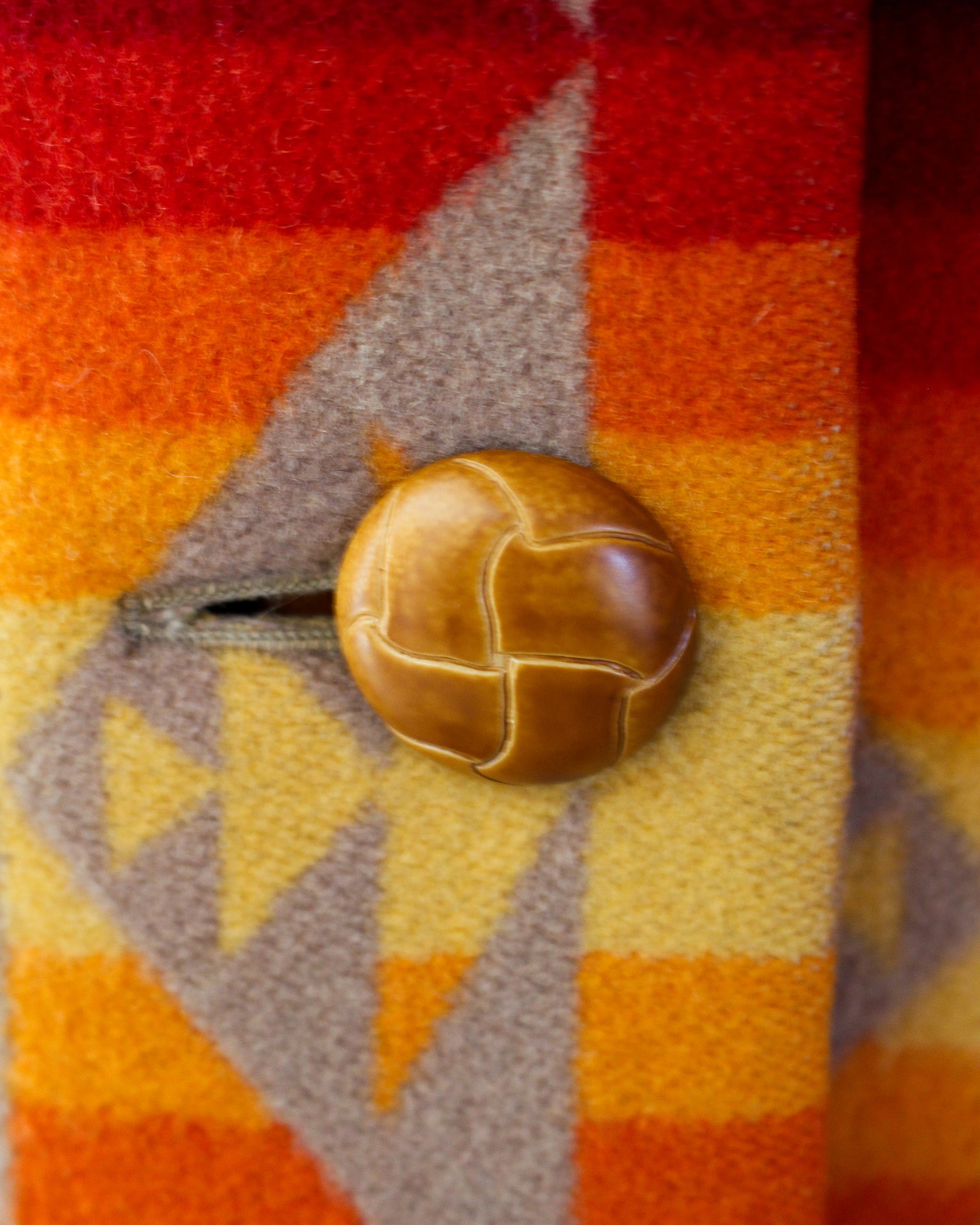 Close-up of a button on a fabric with red, orange, and yellow geometric pattern
