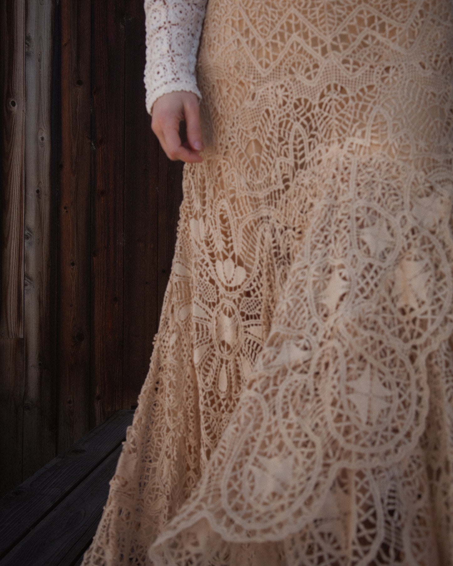 Close-up of a beige lace dress with a wooden background