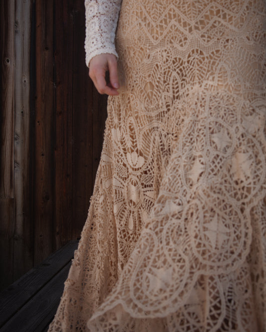 Close-up of a beige lace dress with a wooden background
