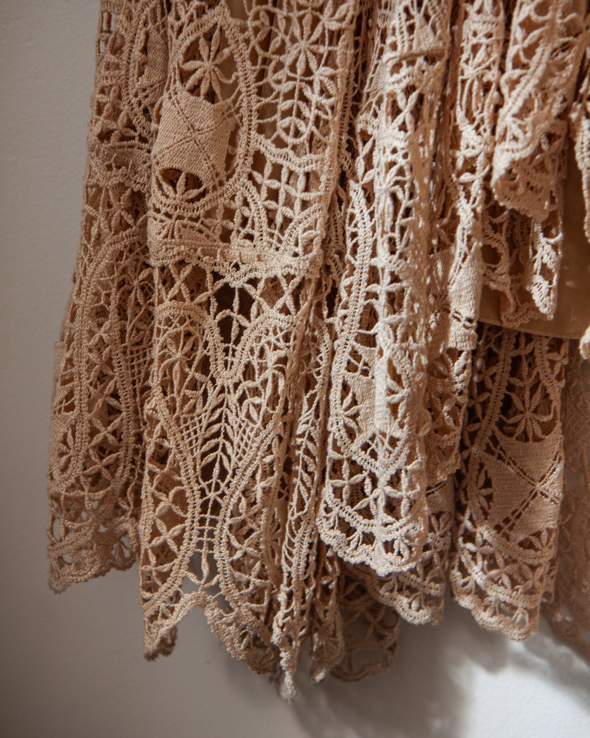 Close-up of a beige lace fabric with intricate patterns on a neutral background
