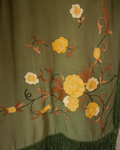 Embroidered floral design on a green fabric with yellow, white, and brown flowers.