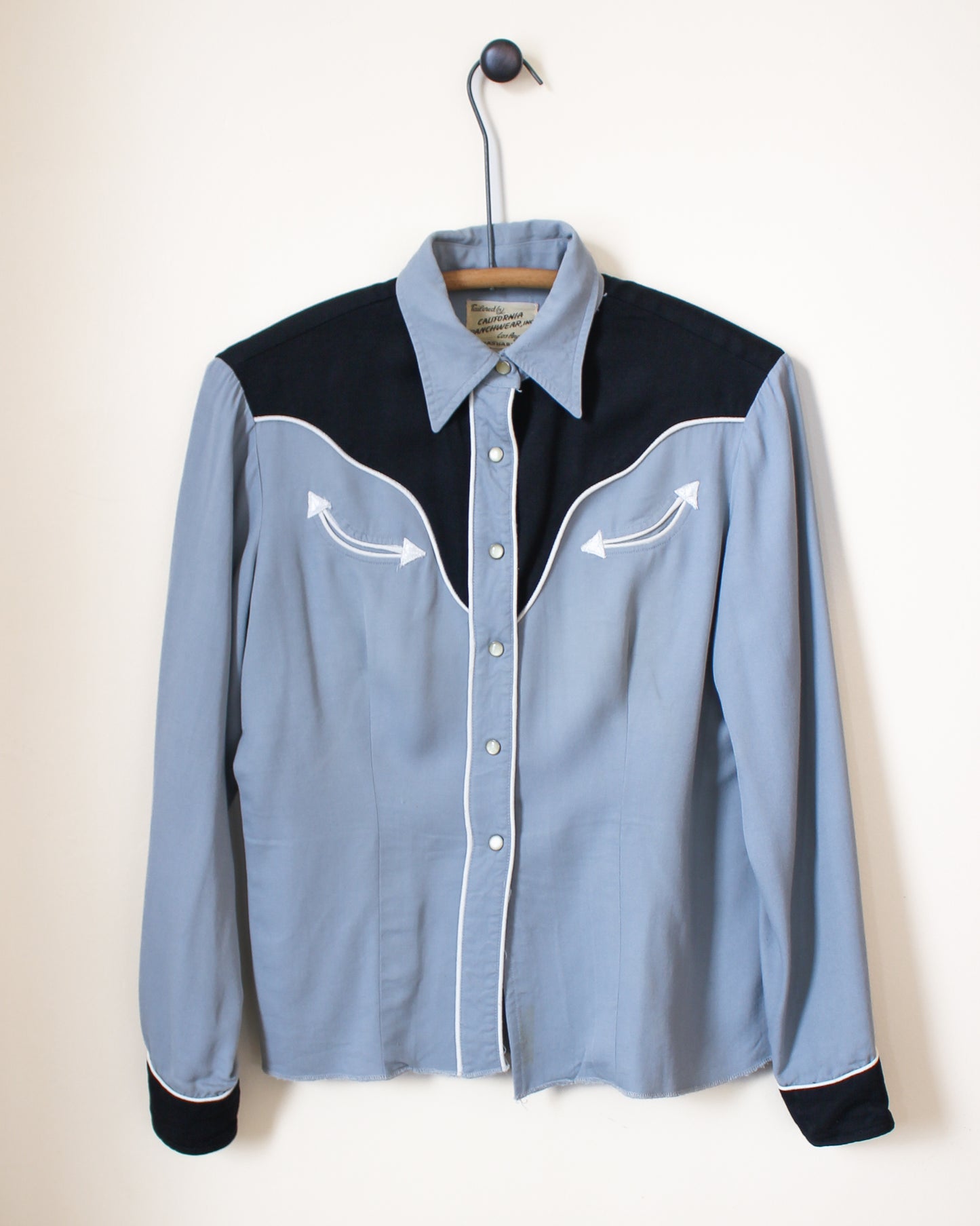 Blue and black button-up shirt on a hanger against a white background