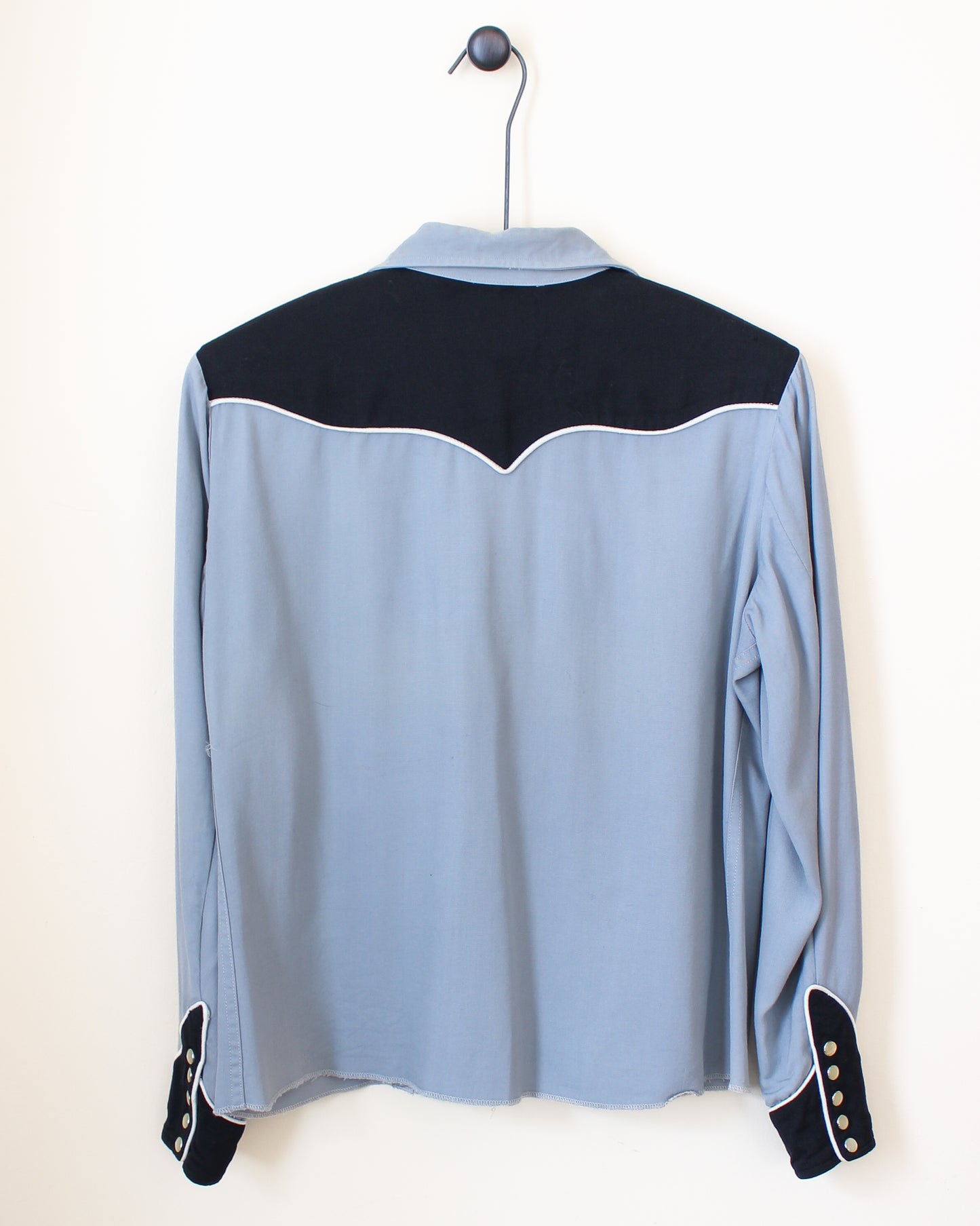 Light blue shirt with black accents on a hanger against a white background