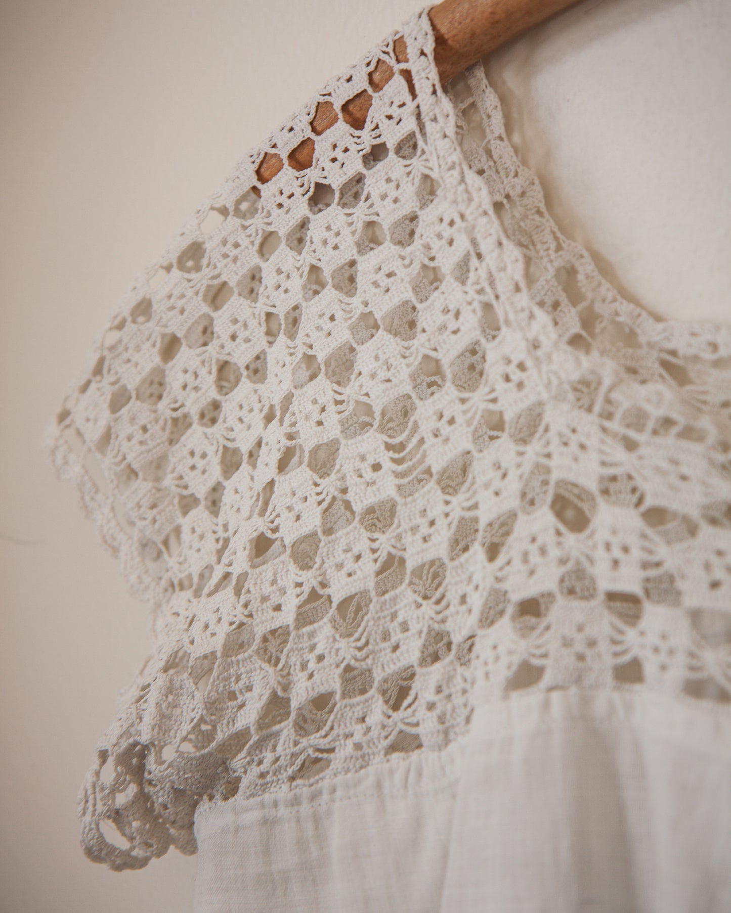 Close-up of a lace garment on a wooden hanger against a neutral background