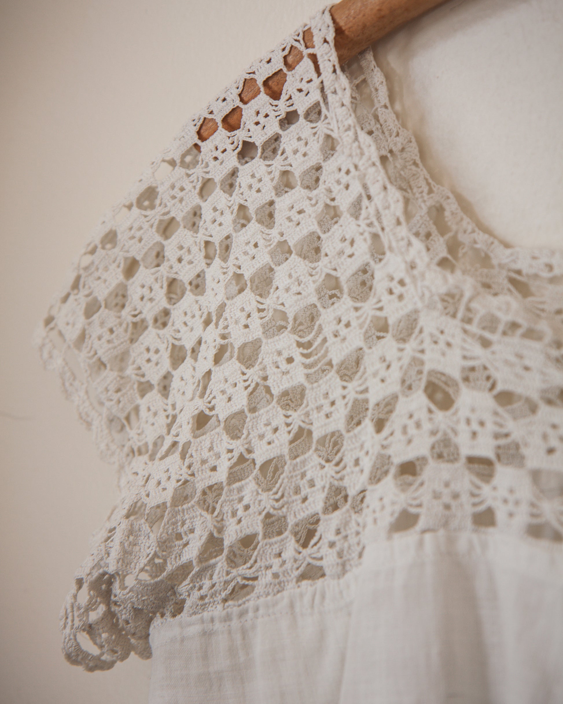 Close-up of a lace garment on a wooden hanger against a neutral background