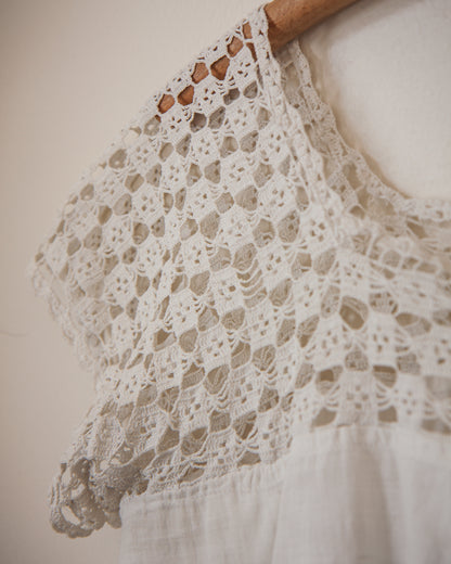 Close-up of a lace garment on a wooden hanger against a neutral background