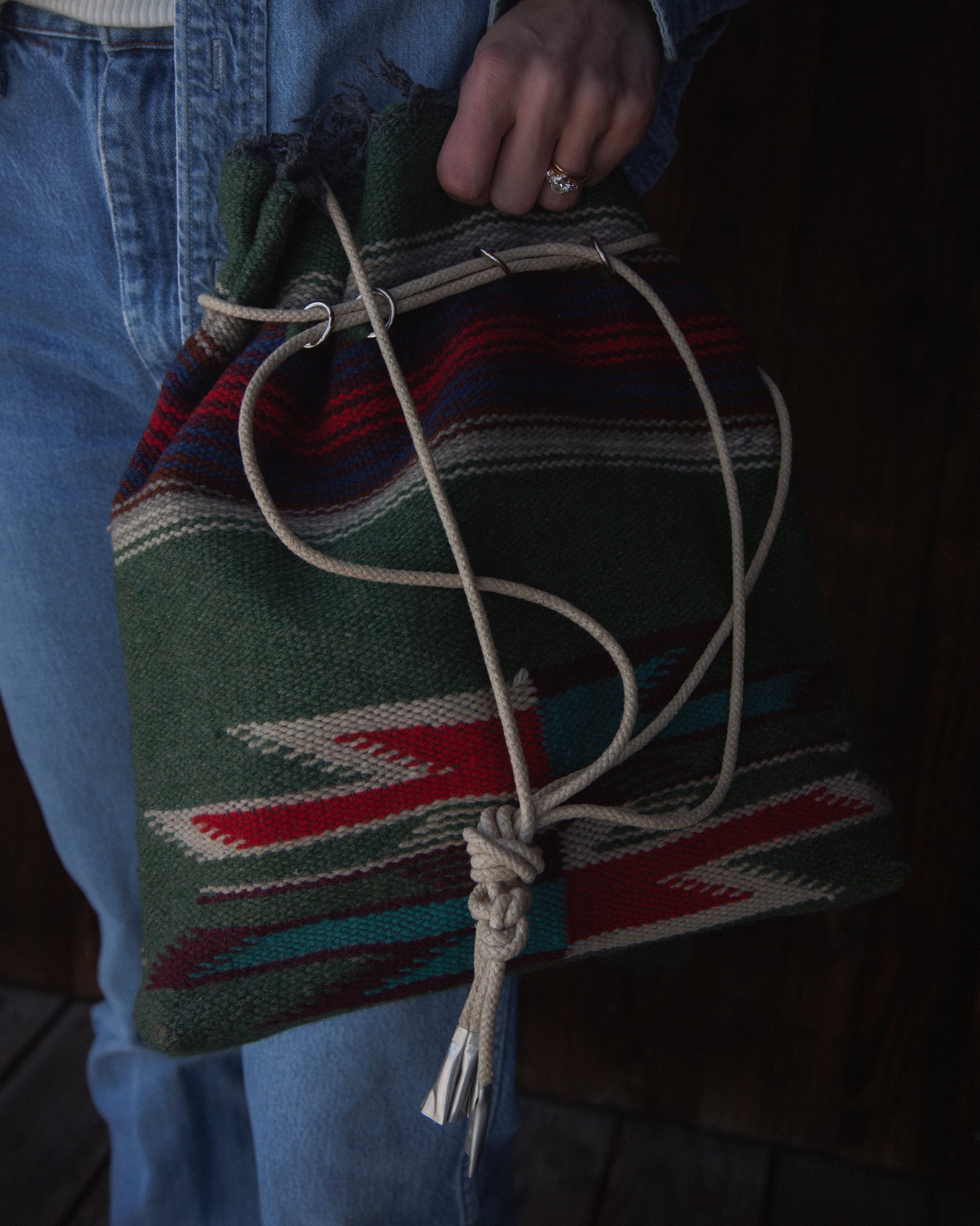 Person holding a colorful woven bag with a patterned background