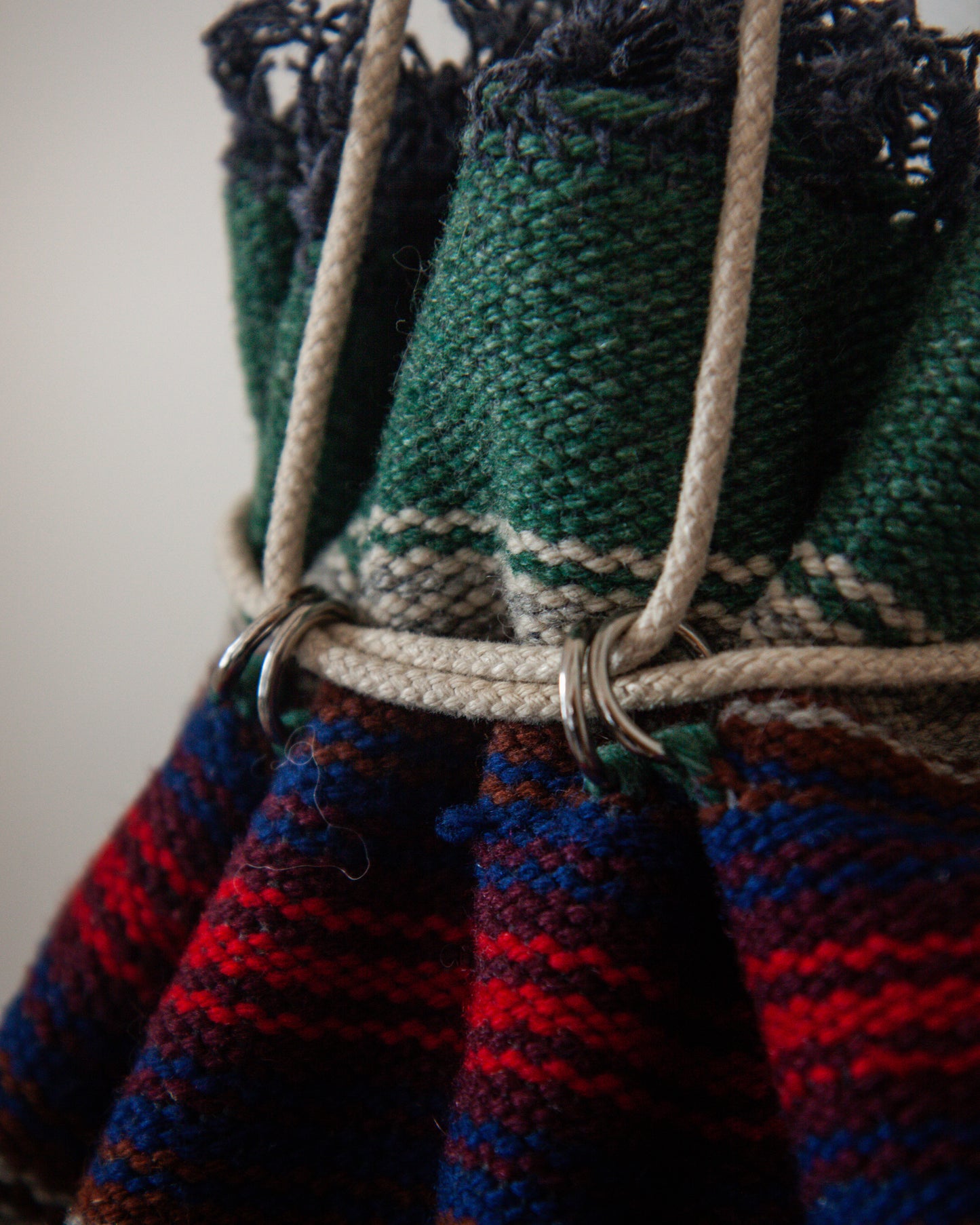 Close-up of a knitted bag with colorful patterns and a strap.