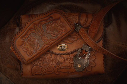 Brown leather bag with intricate designs and a padlock on a dark background