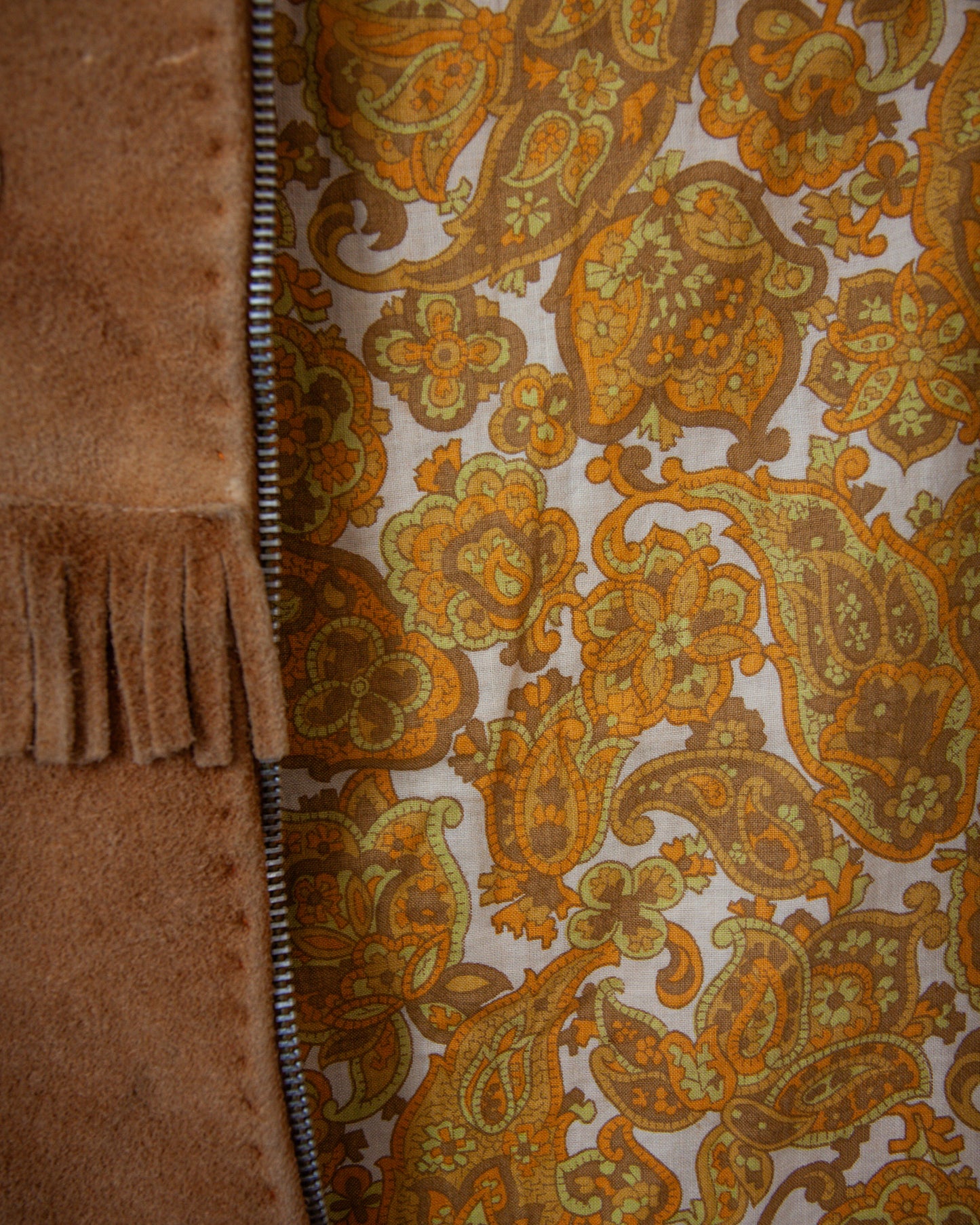 Close-up of a fabric with a paisley pattern and a brown textured material on the left.