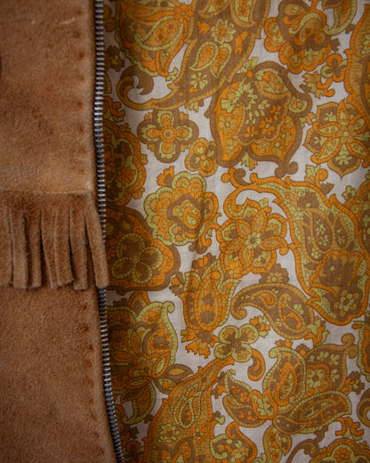 Close-up of a fabric with a paisley pattern and a brown textured material on the left.