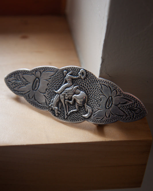 Decorative metal belt buckle with intricate designs on a wooden surface