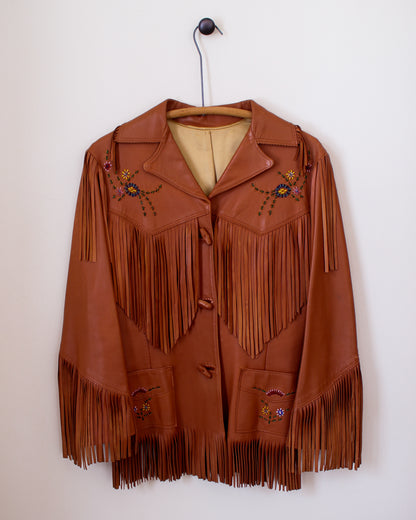 Brown leather jacket with fringe and embroidery on a white wall