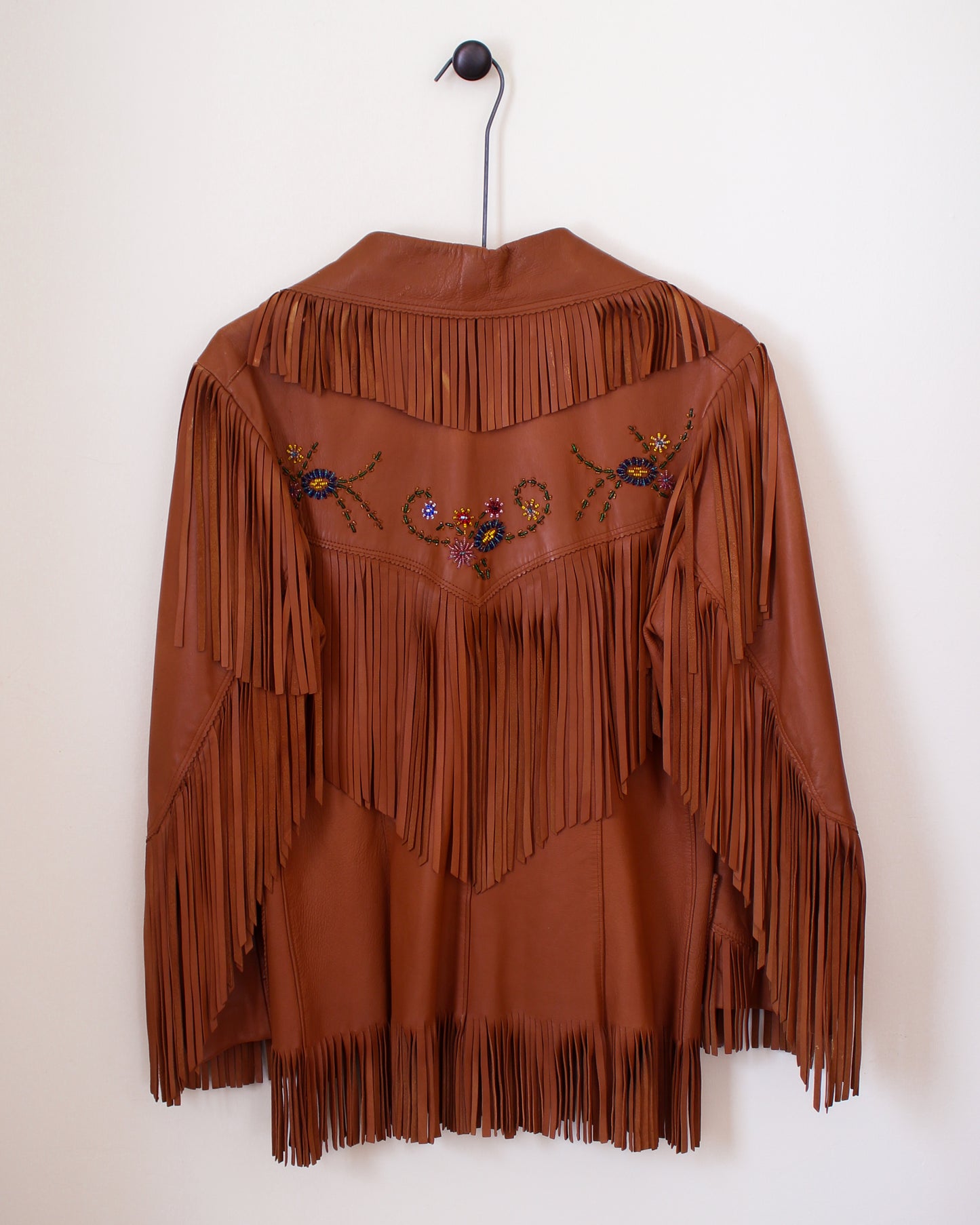 Brown fringed jacket with bead embellishments on a white background