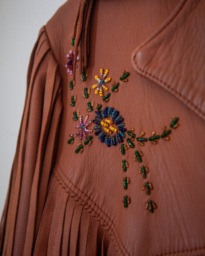 Brown leather jacket with colorful beadwork on a plain background