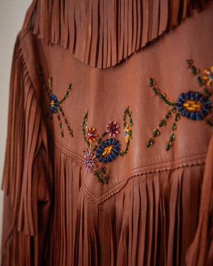 Brown leather jacket with fringe and colorful beadwork on a plain background