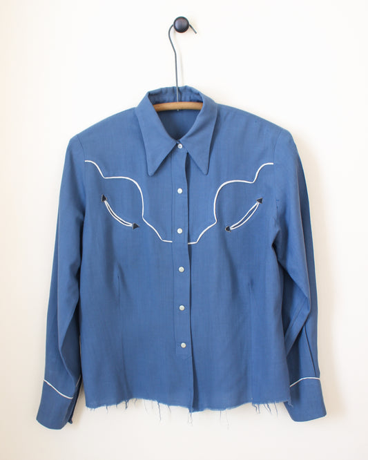 Blue shirt with white embroidery on a hanger against a white background