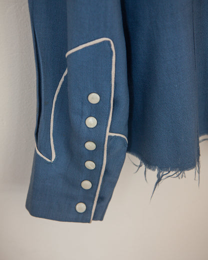 Blue fabric with white piping and buttons on a plain background