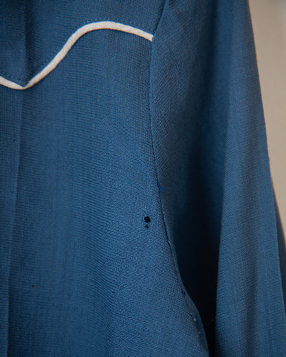 Close-up of a blue garment with white stitching on a neutral background
