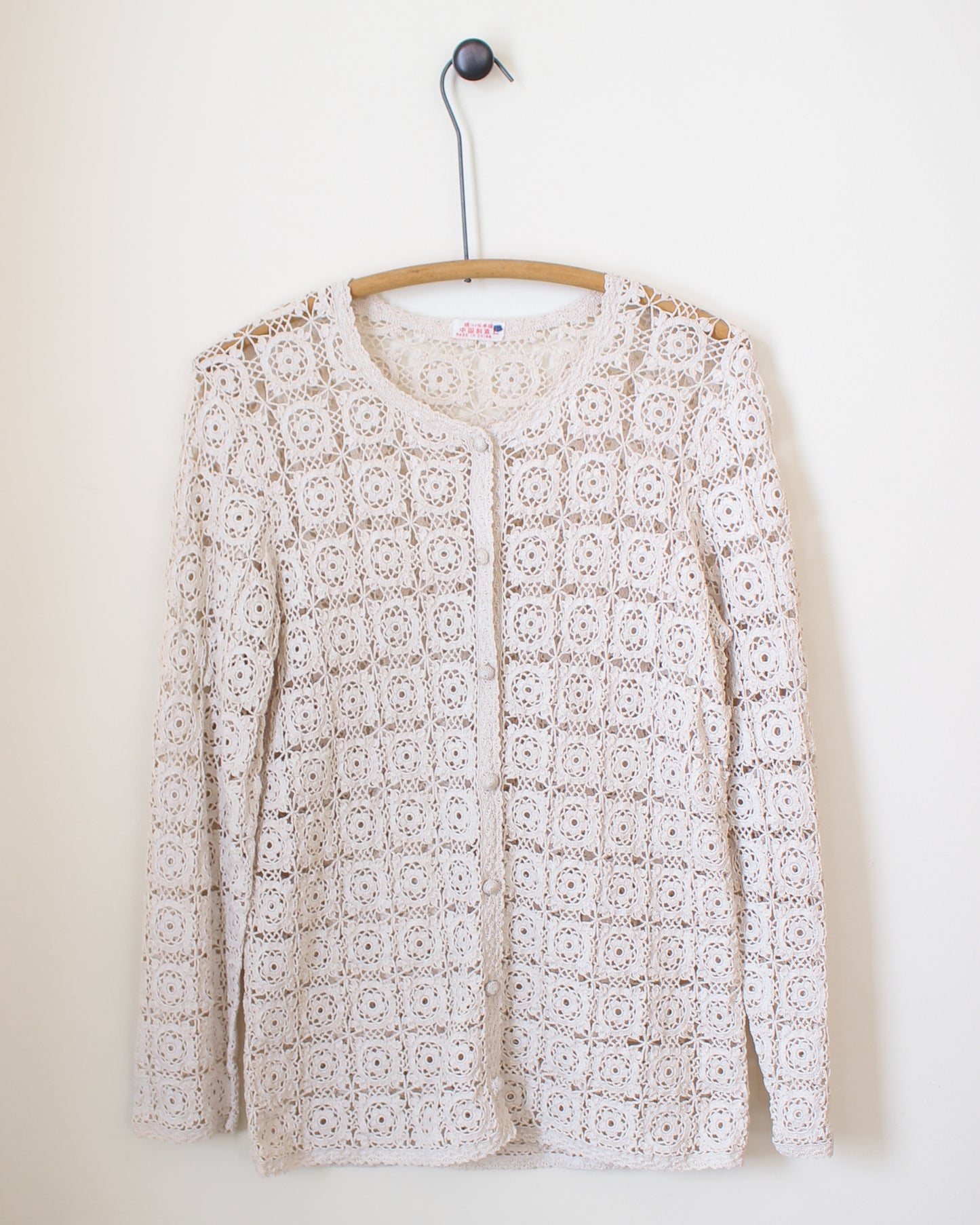 White lace cardigan on a hanger against a white background