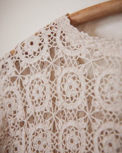 Close-up of beige lace fabric on a wooden hanger against a neutral background