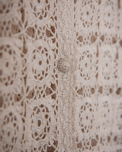 Close-up of beige lace fabric with a button in the center
