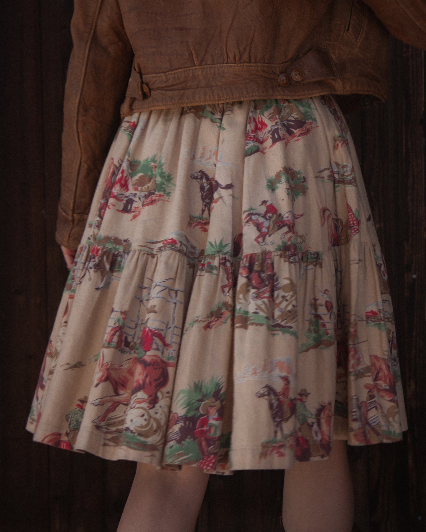 Skirt with vintage-style horse and rider pattern worn by a person in a brown jacket.