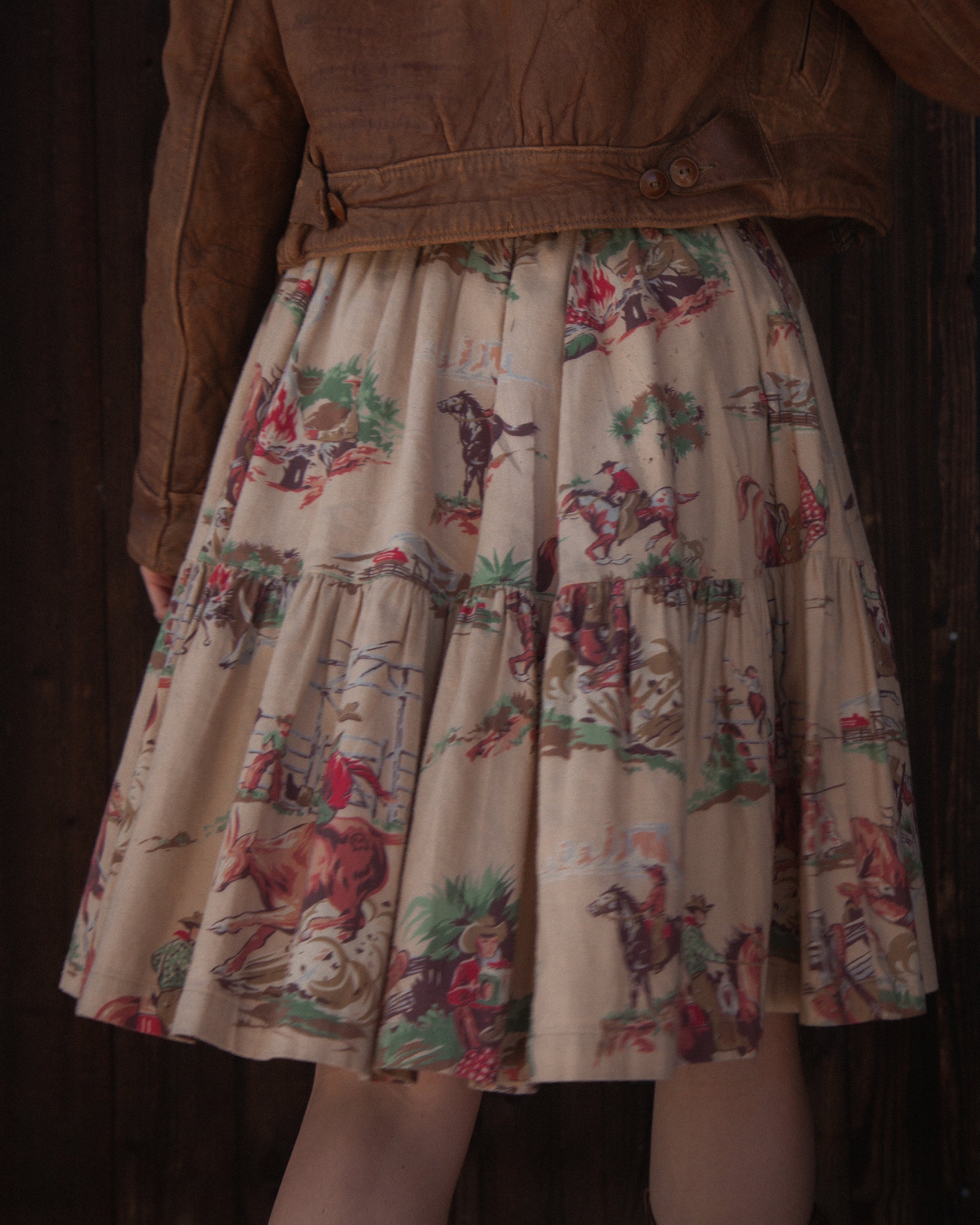 Skirt with vintage-style horse and rider pattern worn by a person in a brown jacket.