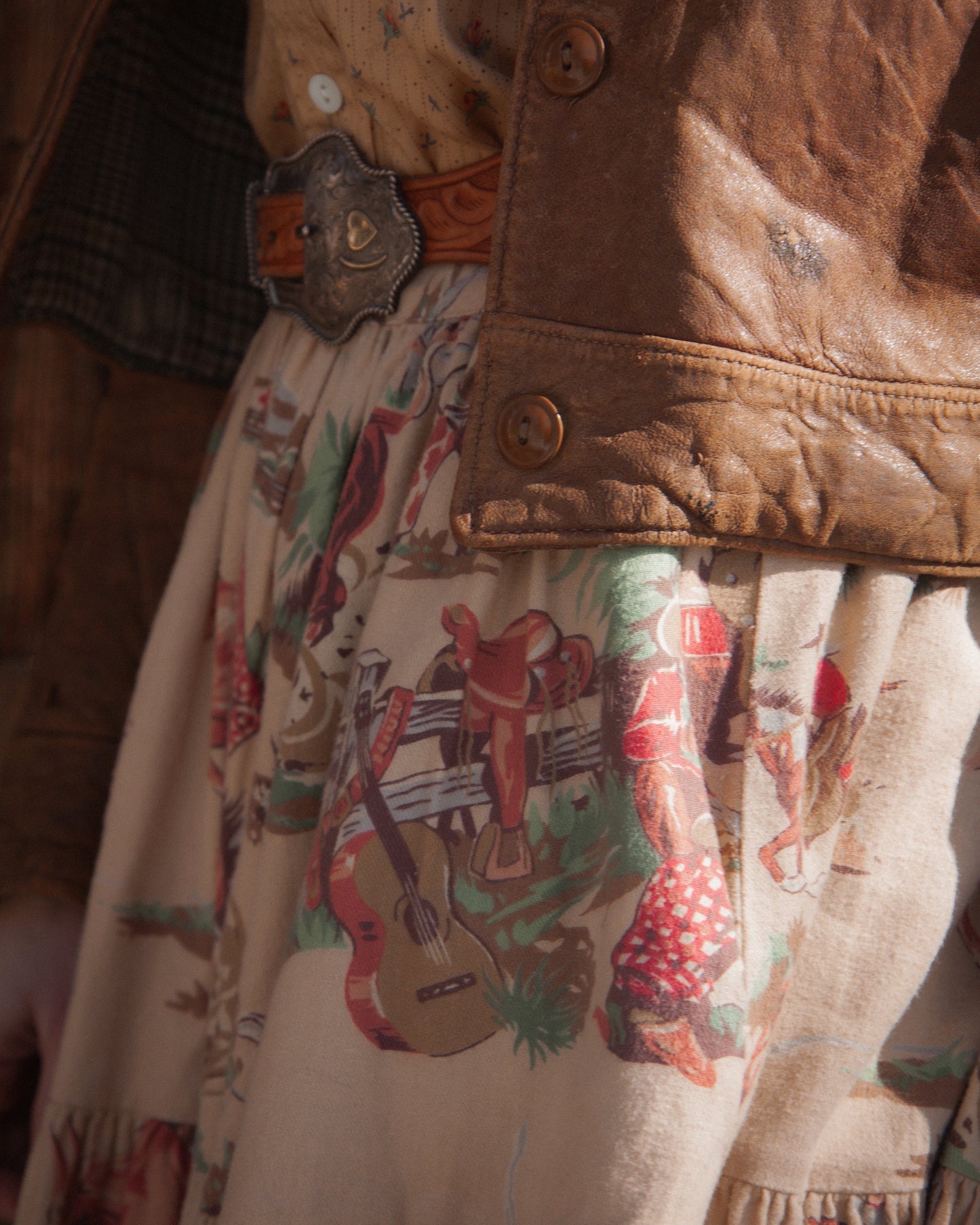 Close-up of a person wearing a brown jacket with a patterned shirt underneath, featuring cowboy graphics.