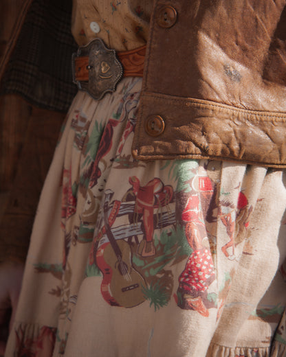 Close-up of a person wearing a brown jacket with a patterned shirt underneath, featuring cowboy graphics.