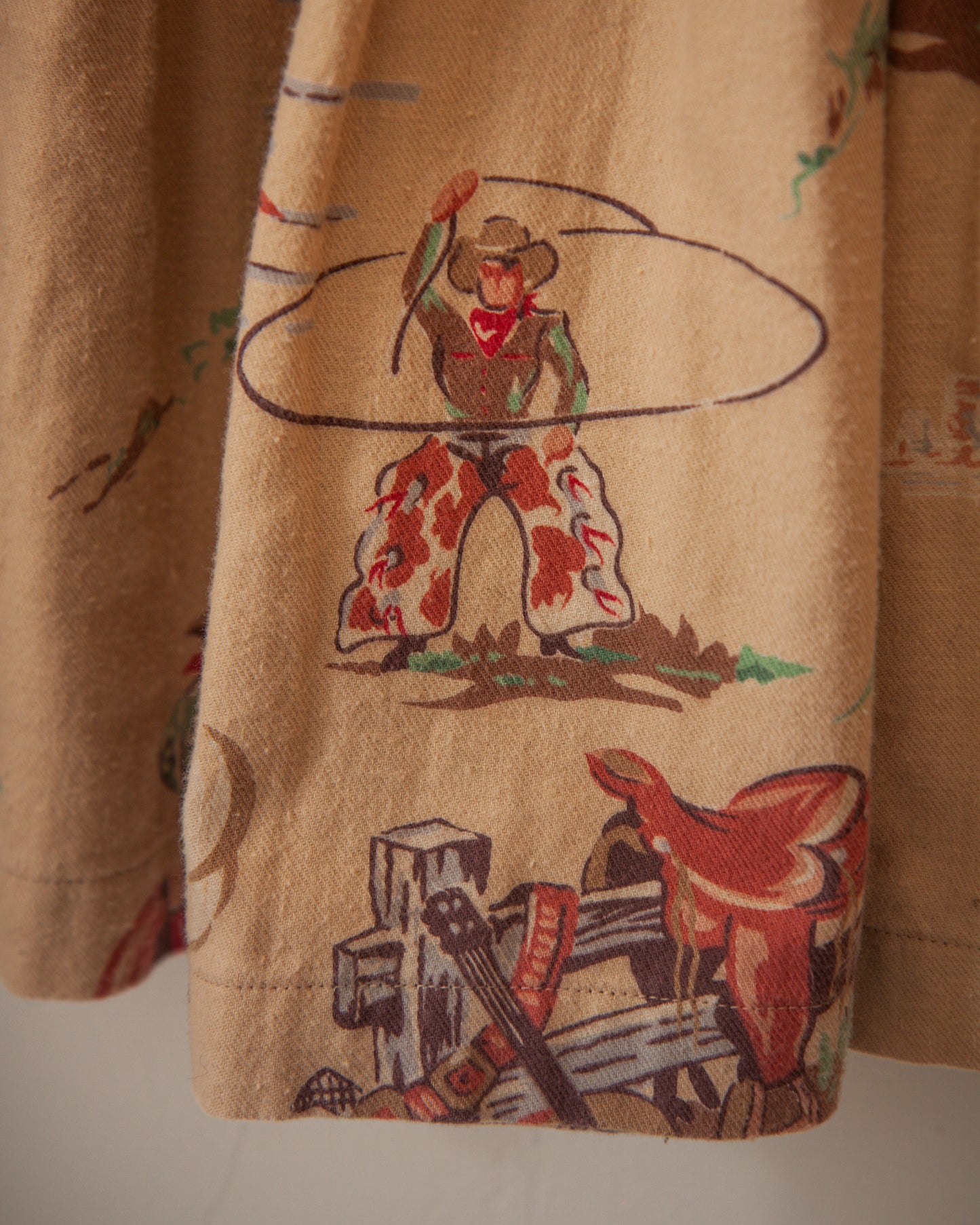 Close-up of a brown fabric with embroidered cowboy design on a plain background