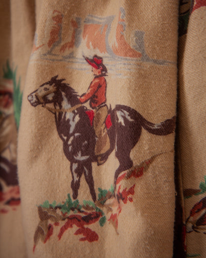 Close-up of a fabric with a cowboy riding a horse design on a beige background.