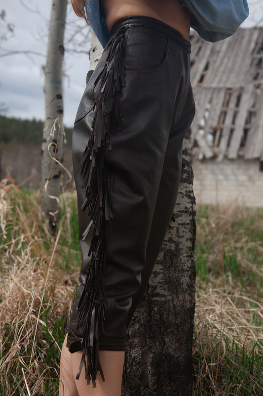 Person wearing black leather pants with fringe in a natural setting
