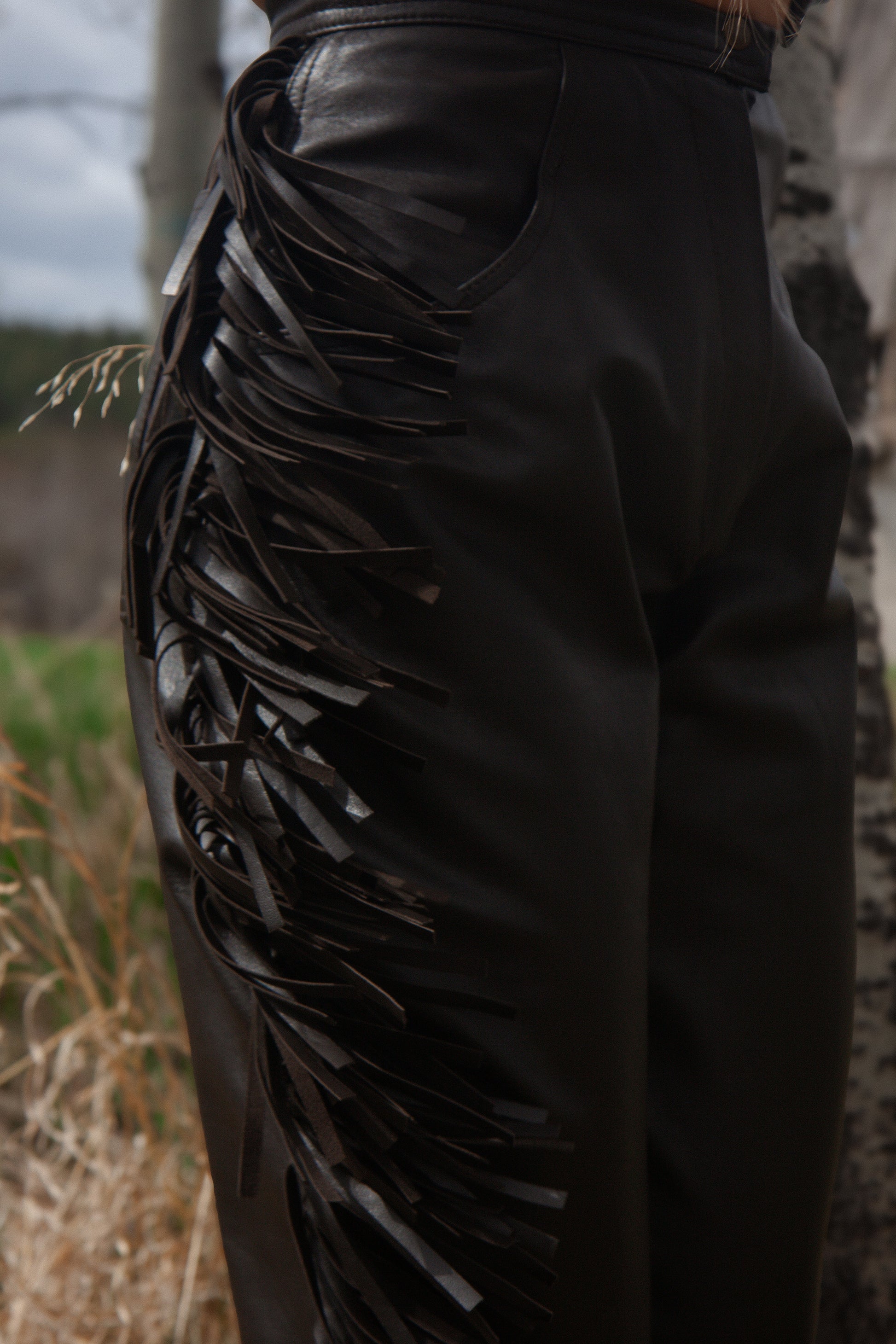 Black leather pants with decorative elements in a natural setting