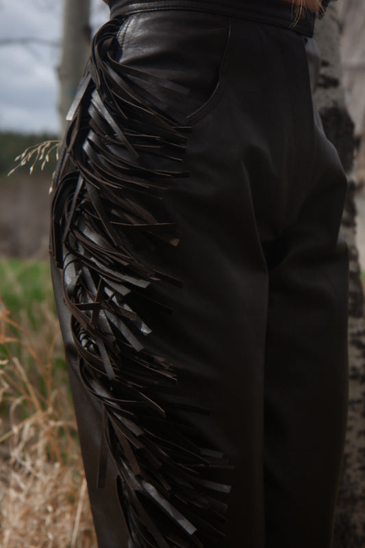 Black leather pants with decorative elements in a natural setting