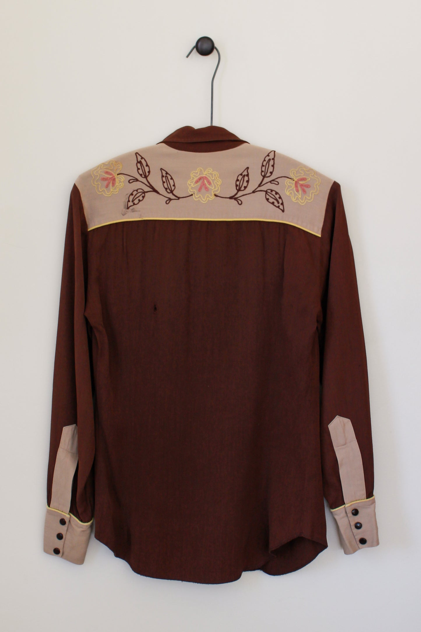 Brown shirt with embroidered details on a white background