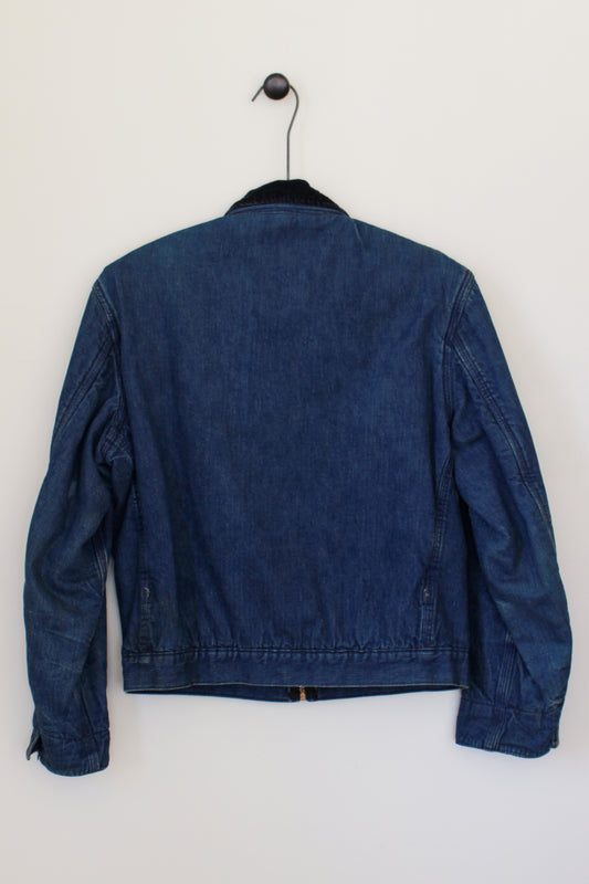 Blue denim jacket on a hanger against a white wall