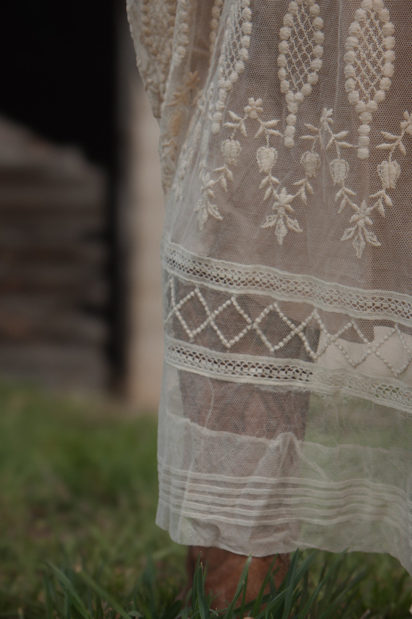 Close-up of a white lace dress with intricate patterns on grass.